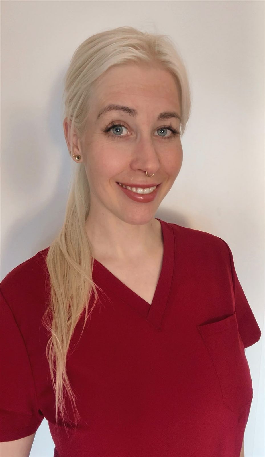 Porträt von Lisa Riemer in roter Praxiskleidung